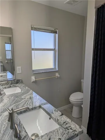 Dual vanity with undermount sinks, brushed nickel faucets, and a patterned stone countertop