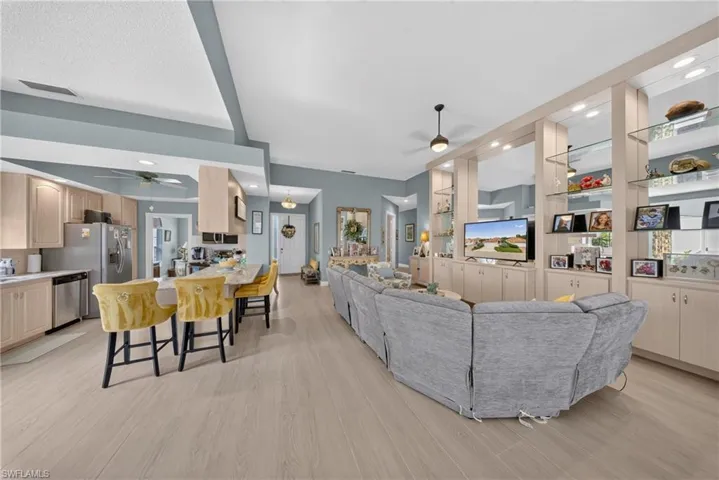 Open-concept living area featuring light wood-finish flooring, vaulted ceilings, and a neutral color palette
