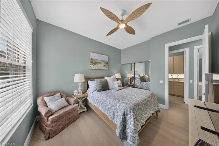 Bedroom with wood-finish flooring, a decorative ceiling fan, and a window with horizontal blinds