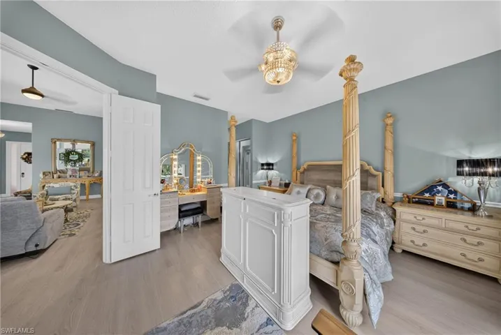 Spacious room featuring wood-finish flooring, vaulted ceilings, and a decorative ceiling fan with lighting