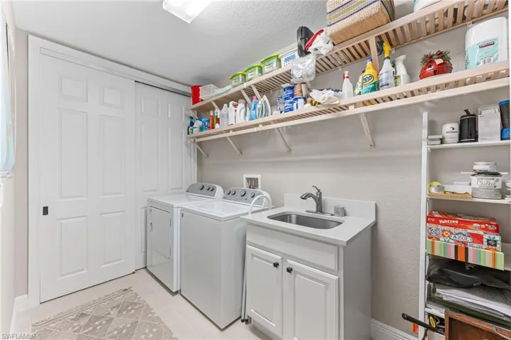 Laundry room featuring independent washer and dryer, cabinet space, a textured ceiling, and light tile patterned floors