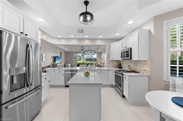 Kitchen with stainless steel appliances, a peninsula, white cabinetry, a kitchen island, and recessed lighting