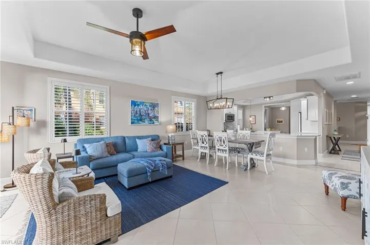 Living area with a tray ceiling, light tile patterned flooring, and ceiling fan