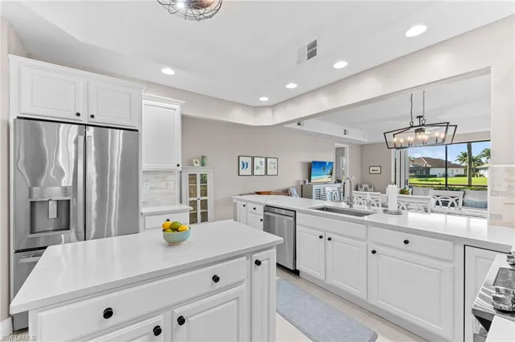 Kitchen featuring hanging light fixtures, white cabinets, light stone countertops, appliances with stainless steel finishes, and recessed lighting