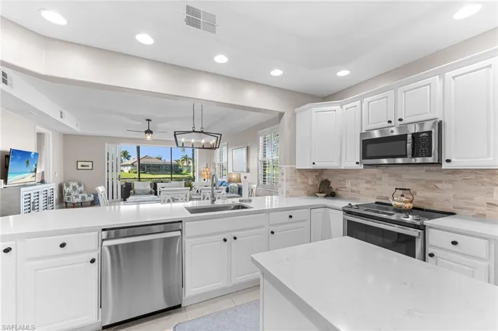 Kitchen with open floor plan, a chandelier, white cabinetry, appliances with stainless steel finishes, and recessed lighting