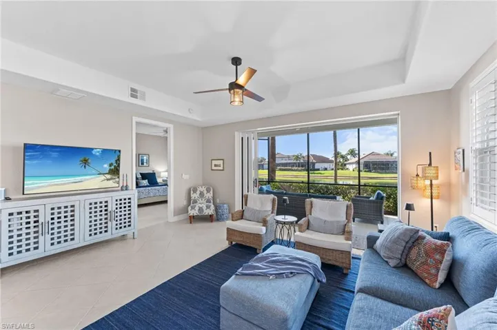 Tiled living room with a tray ceiling and ceiling fan