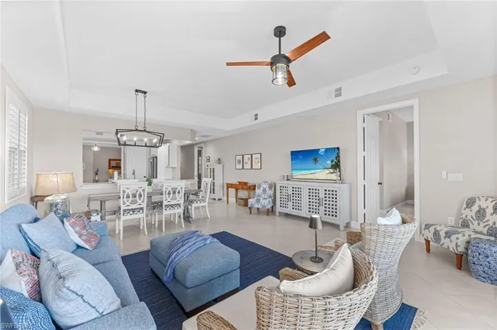 Tiled living area featuring a raised ceiling and a ceiling fan