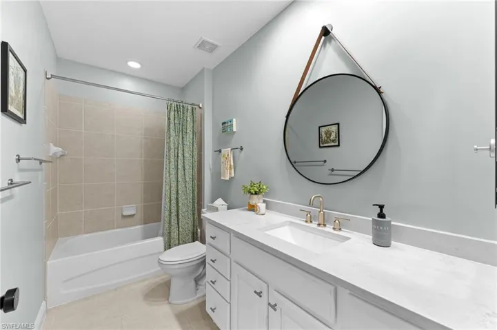 Full bath with shower / bath combo, vanity, and light tile patterned flooring