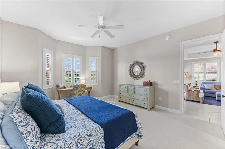 Carpeted bedroom featuring multiple windows, ceiling fan, and a desk