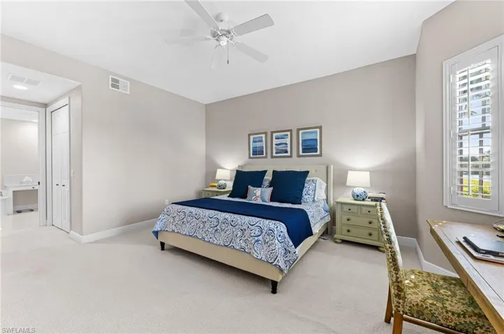 Bedroom featuring light carpet, ceiling fan, and a desk
