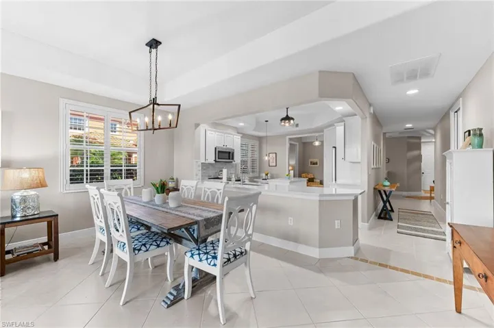 Dining space featuring light tile patterned floors, recessed lighting, a raised ceiling, and a chandelier