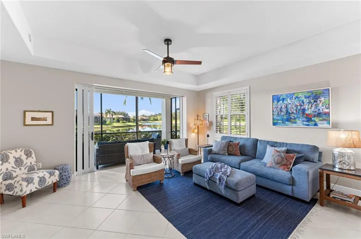 Living area featuring a water view, a raised ceiling, a ceiling fan, and light tile patterned floors