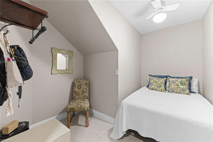 Bedroom with light tile patterned floors, ceiling fan, and vaulted ceiling
