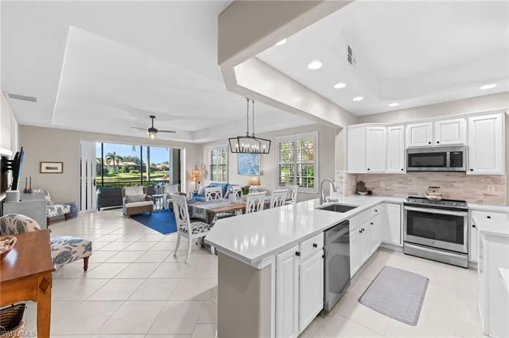 Kitchen featuring a raised ceiling, open floor plan, white cabinets, and recessed lighting
