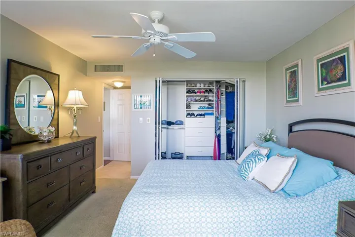 Bedroom with a closet, ceiling fan, and light colored carpet