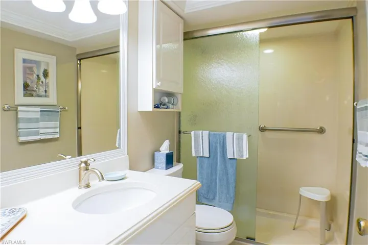 Bathroom featuring vanity, toilet, a shower with shower door, and crown molding