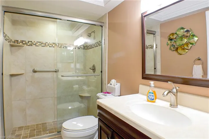 Bathroom featuring walk in shower, vanity, ornamental molding, and toilet