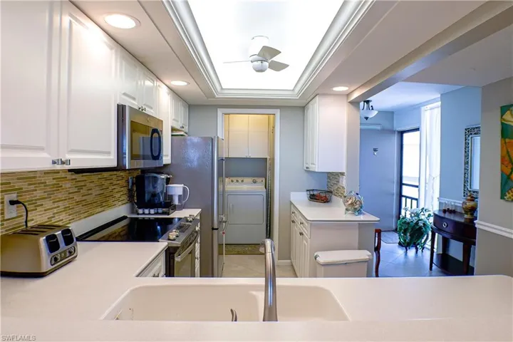 Kitchen featuring kitchen peninsula, sink, white cabinets, and appliances with stainless steel finishes