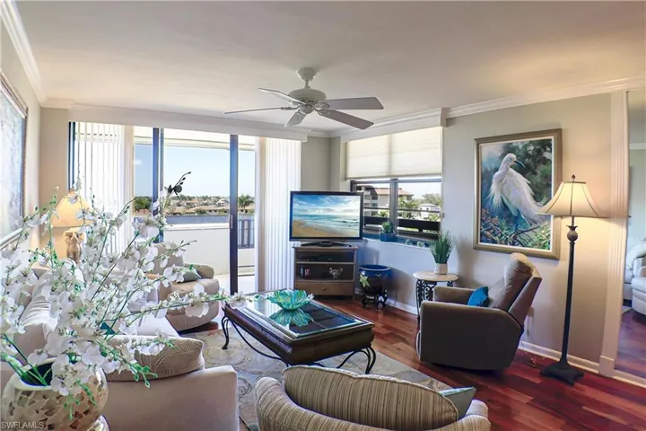 Living room featuring ornamental molding, ceiling fan, and dark wood-type flooring