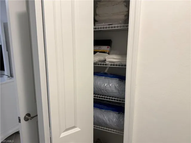 Storage closet featuring white paneled doors and tiered wire shelving