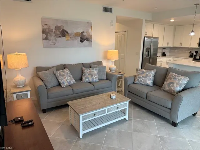 Open-concept interior featuring large-format diagonal tile flooring, white cabinetry, a kitchen island with stone countertops, and recessed lighting