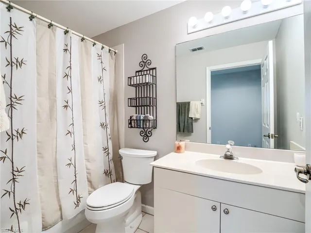 Bathroom with walk in shower, vanity, toilet, and tile patterned flooring
