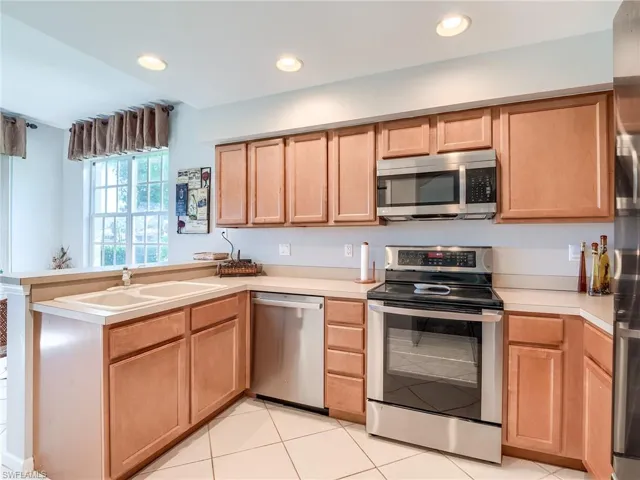 Kitchen featuring sink, light tile patterned flooring, kitchen peninsula, and stainless steel appliances