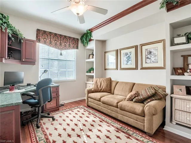 Office area featuring dark wood-type flooring, built in shelves, and ceiling fan