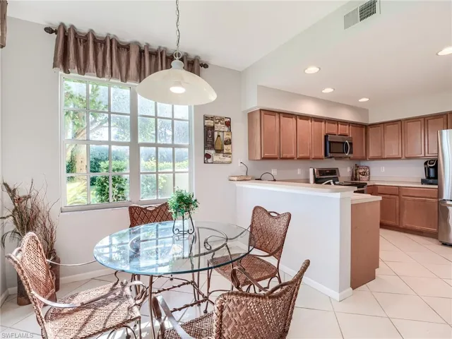 Kitchen with light tile patterned floors, appliances with stainless steel finishes, decorative light fixtures, and kitchen peninsula