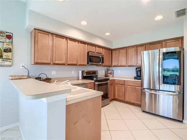 Kitchen with sink, kitchen peninsula, stainless steel appliances, and light tile patterned floors