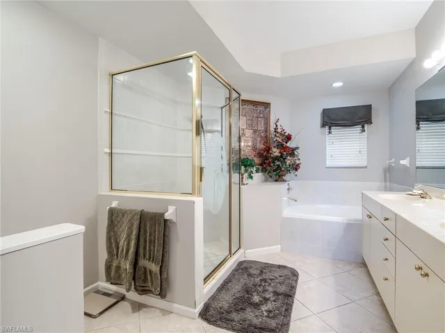 Bathroom featuring vanity, tile patterned flooring, and plus walk in shower