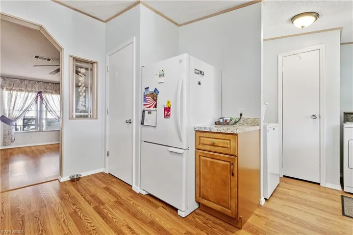 Kitchen featuring freestanding refrigerator, a textured ceiling, light countertops, light wood-style floors, and wood finish cabinets