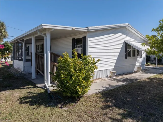 View of side of home with a sunroom and a lawn