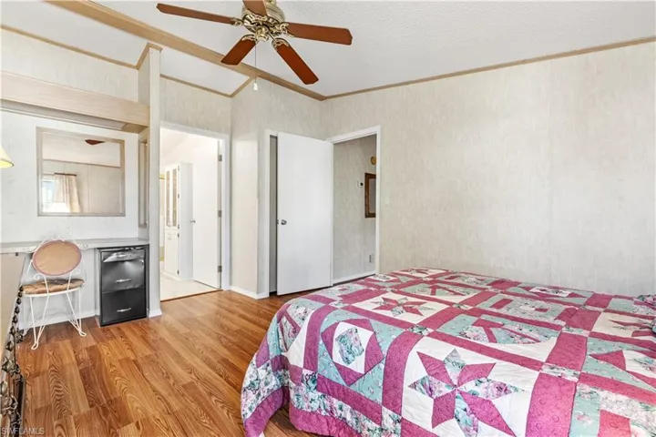 Bedroom featuring crown molding, light wood-style floors, a ceiling fan, and a textured ceiling