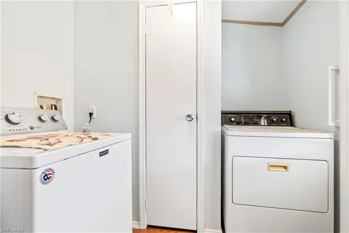 Laundry area featuring washer and dryer, ornamental molding, and light wood finished floors