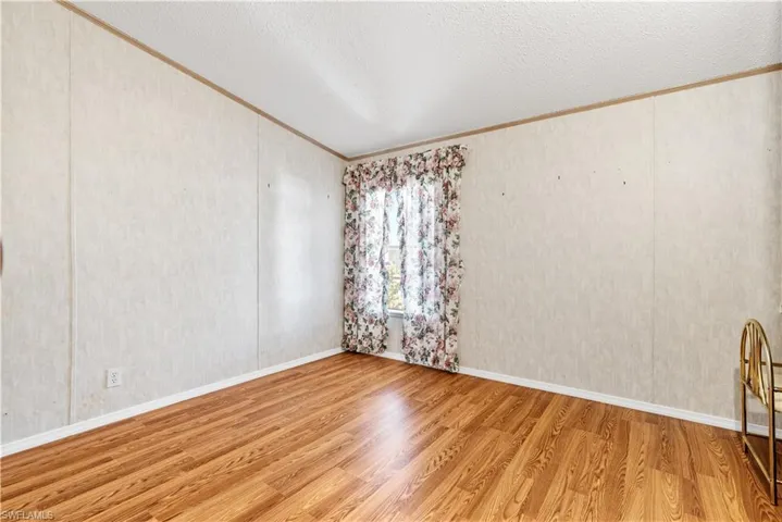 Unfurnished room with wood finished floors, ornamental molding, and a textured ceiling