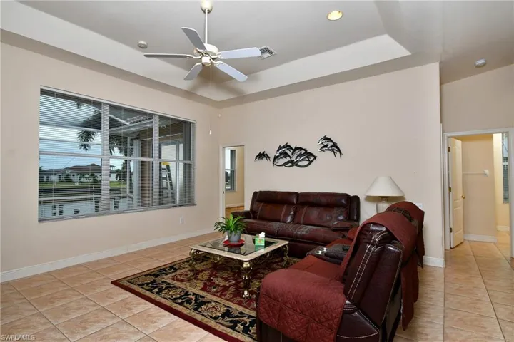 Living area featuring large multi-panel windows, ceramic tile flooring, and a tray ceiling with recessed lighting