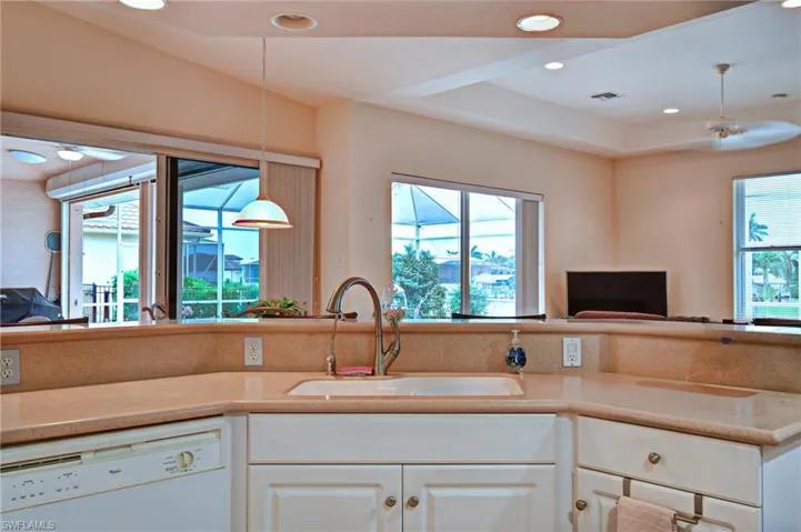 Kitchen featuring light-toned countertops, white cabinetry with decorative hardware, and a double basin sink with a high-arch faucet