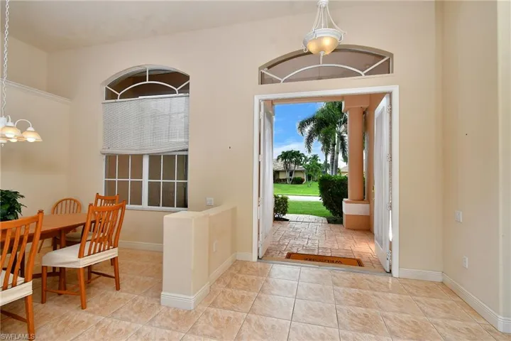 Entryway featuring double doors, an arched transom window, and tiled flooring