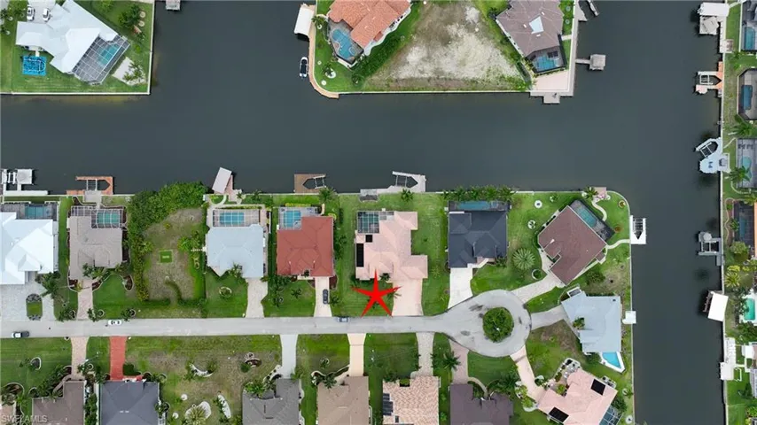 Waterfront property featuring a private boat dock, concrete drive, and a manicured lawn