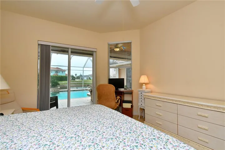 Bedroom featuring sliding glass doors opening to a screened pool area with water frontage