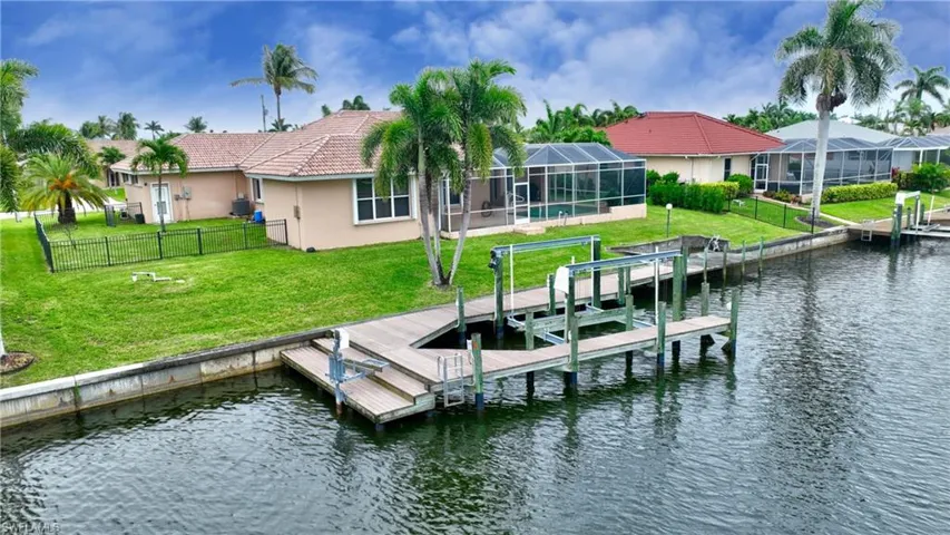 Waterfront property featuring a private dock with boat lift, screened-in lanai, and a tiled roof residence