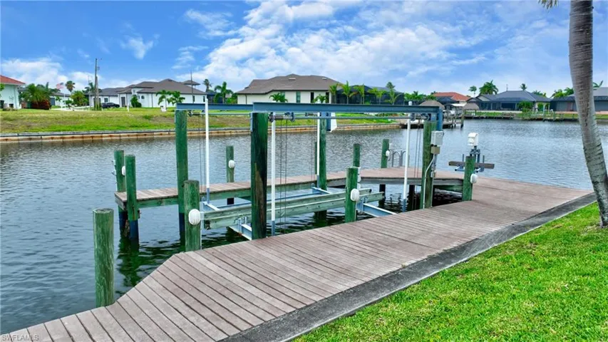 Waterfront property featuring a wooden dock, boat lift, and canal access