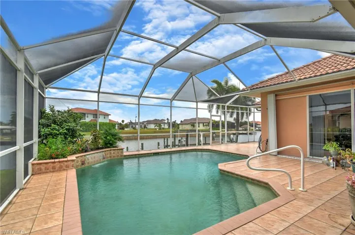 Screened pool enclosure featuring an in-ground swimming pool with an integrated water feature and a tiled pool deck