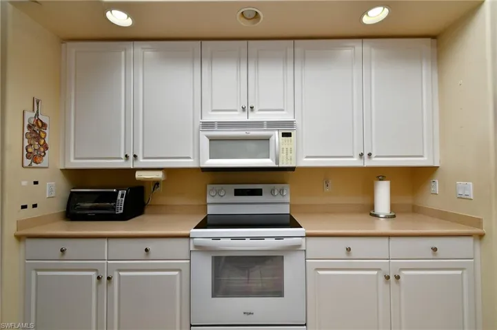 Kitchen featuring white shaker-style cabinetry, a built-in microwave, white electric range, and recessed lighting