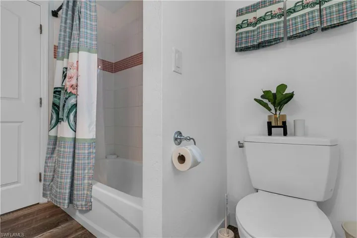 Tub and shower combination featuring white subway tile surround with a decorative accent band and a white porcelain tub