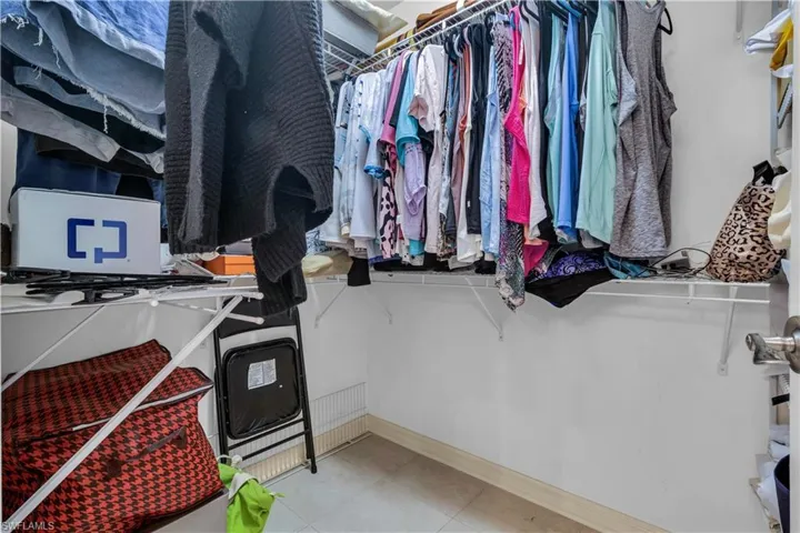 Walk-in closet featuring white wire shelving, hanging rods, and light-toned flooring