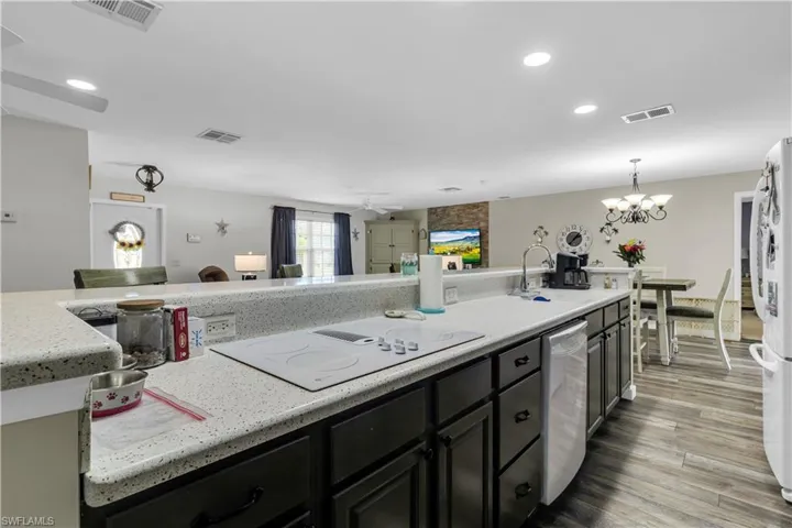 Kitchen featuring dark wood cabinetry, a white speckled countertop, and a built-in cooktop