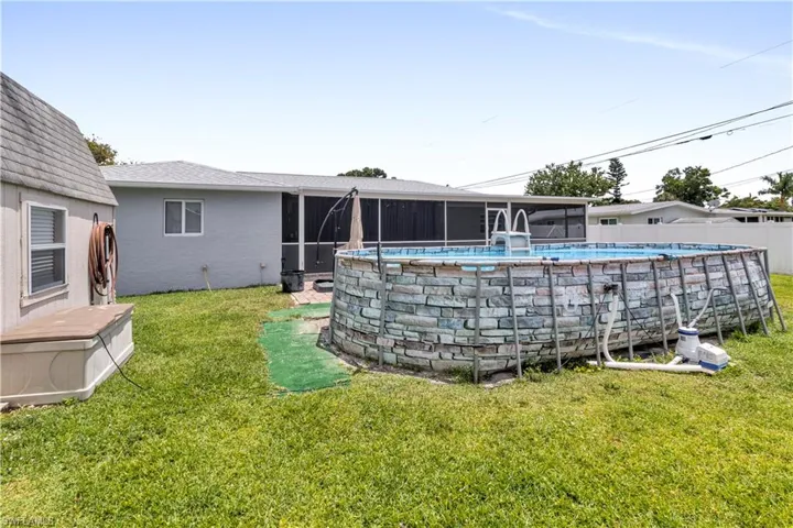 Expansive backyard featuring a large above-ground pool, screened patio, and a separate storage shed