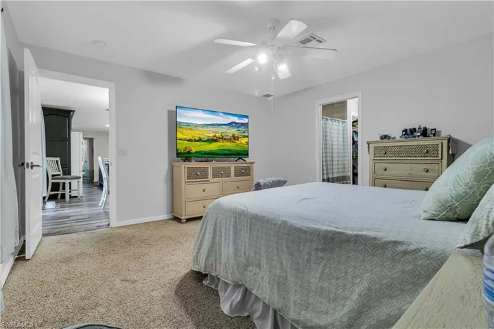 Carpeted room with light gray walls, a white ceiling fan, and white trim